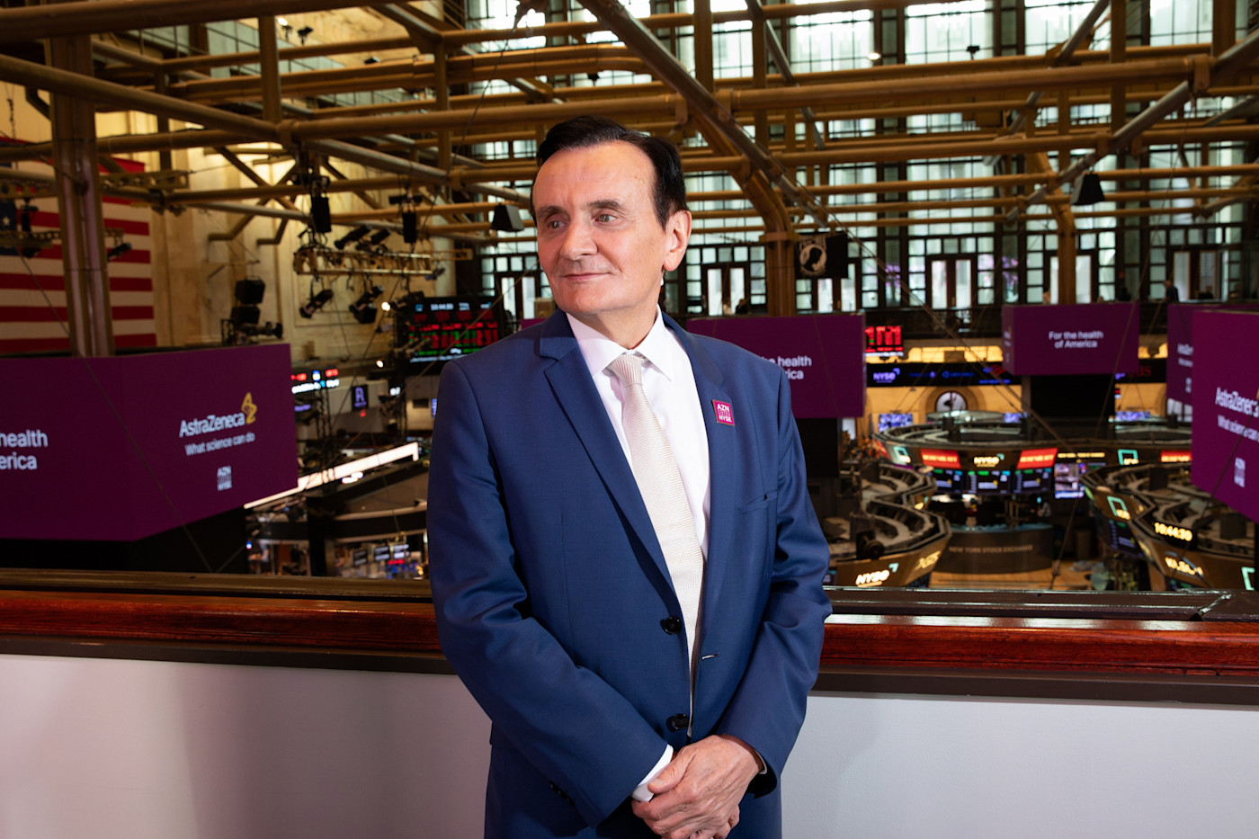 AstraZeneca 최고경영자 Pascal Soriot가 뉴욕증권거래소 거래장 위에 정장을 입고 서 있다.