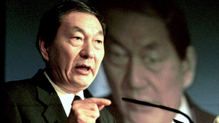 주룽지가 마이크에 대고 말하며 손짓하고 있고, 배경에는 그의 얼굴을 크게 투사한 이미지가 보인다.