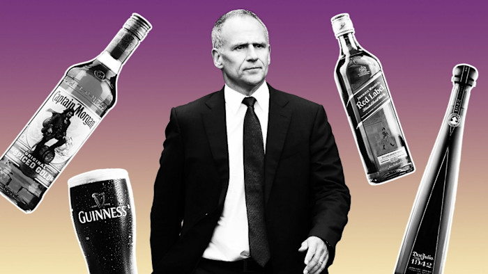 정장을 입은 Dave Lewis가 Captain Morgan, Johnnie Walker, Don Julio 병 이미지와 기네스 맥주 한 잔에 둘러싸여 있다.
