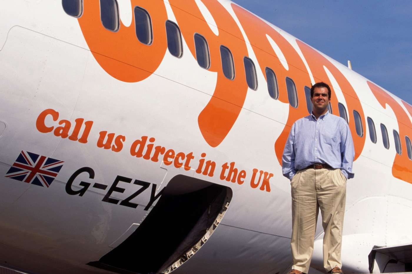 EasyJet 항공기 앞에 서 있는 Stelios Haji-Ioannou, 동체에 항공사 브랜드가 보인다.