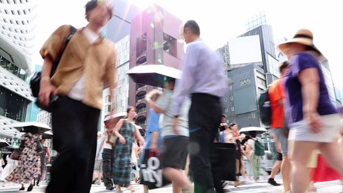 도쿄 긴자 거리에서 폭염 속 햇볕을 피하기 위해 일부가 양산을 쓴 채 길을 건너는 사람들.
