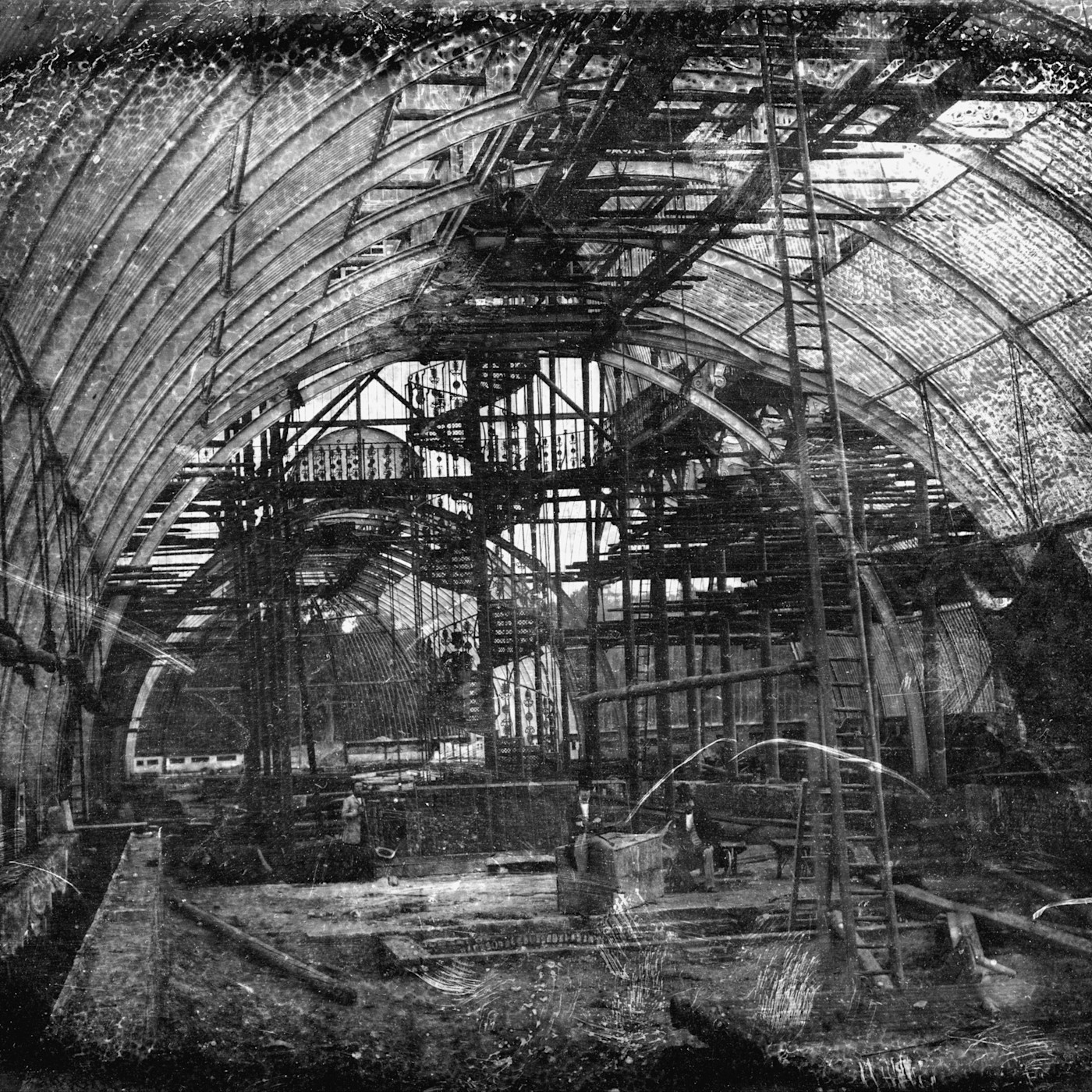 공사 중인 Kew Gardens 팜 하우스 내부, 비계와 건축 자재 사이에 신원 미상의 남성 두 명이 서 있다.