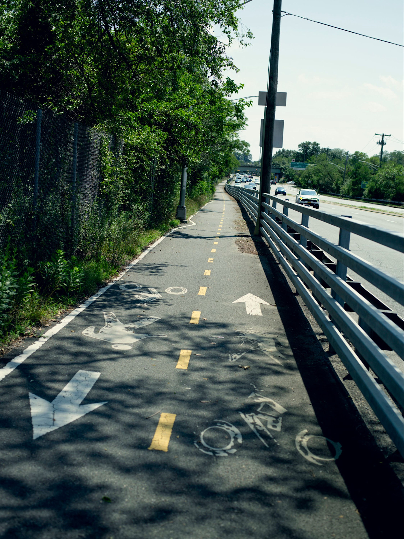 그늘진 보행자·자전거도로가 차량 통행이 많은 Richmond Avenue와 나란히 이어지며, 울타리와 가드레일로 분리돼 있고 보행자와 자전거 이용자를 위한 차선 표시가 있다.
