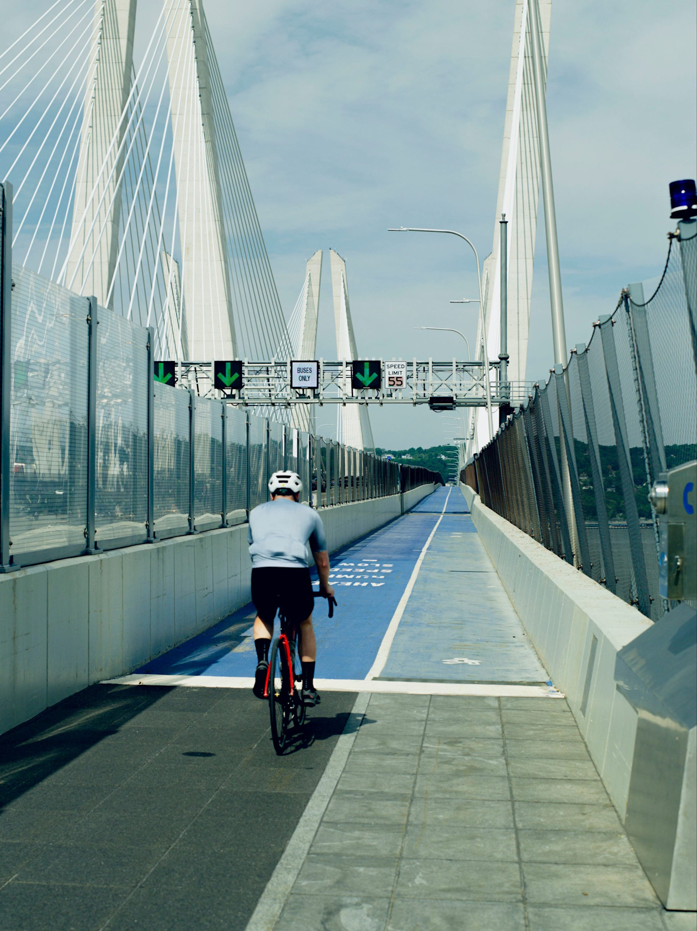 자전거 이용자가 Tappan Zee Bridge 전용 자전거도로를 달리고 있으며, 앞쪽으로 다리의 흰색 사장교 주탑이 보인다.