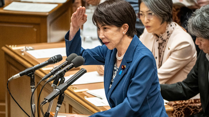 일본 국회 위원회 회의에서 다카이치 사나에가 연단에서 질문에 답하며 손짓하고 있다.