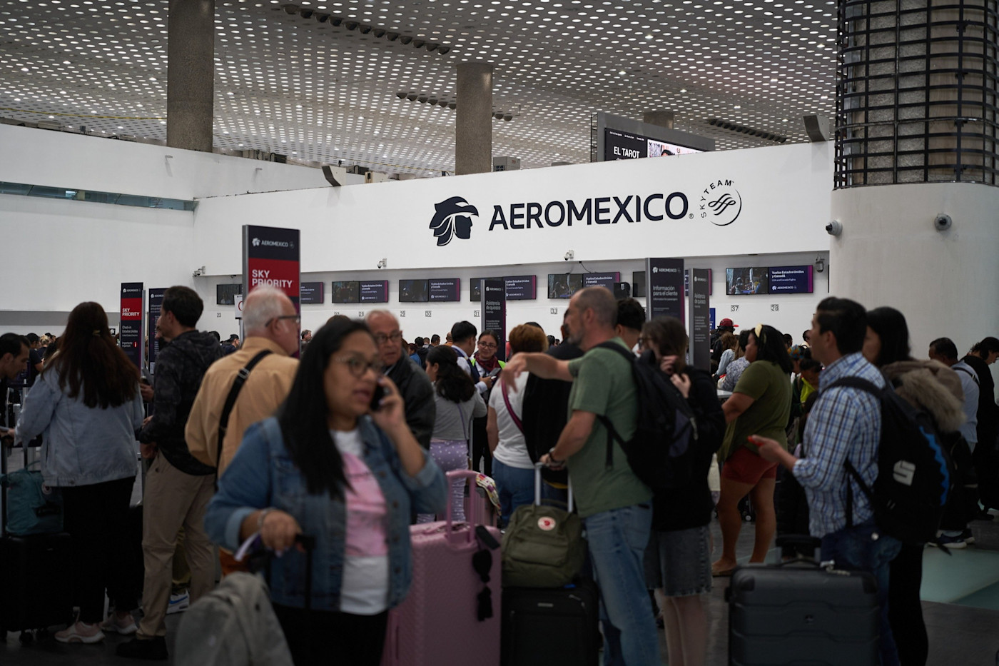 멕시코시티 공항 Grupo Aeromexico 체크인 카운터 근처에서 여행객들이 짐을 들고 기다리고 있다.