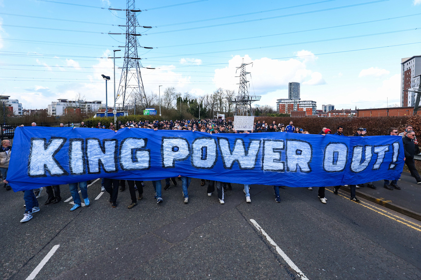 경기장 밖에서 “KING POWER OUT!”이라고 적힌 커다란 파란색 현수막을 들고 행진하는 레스터 시티 팬들.