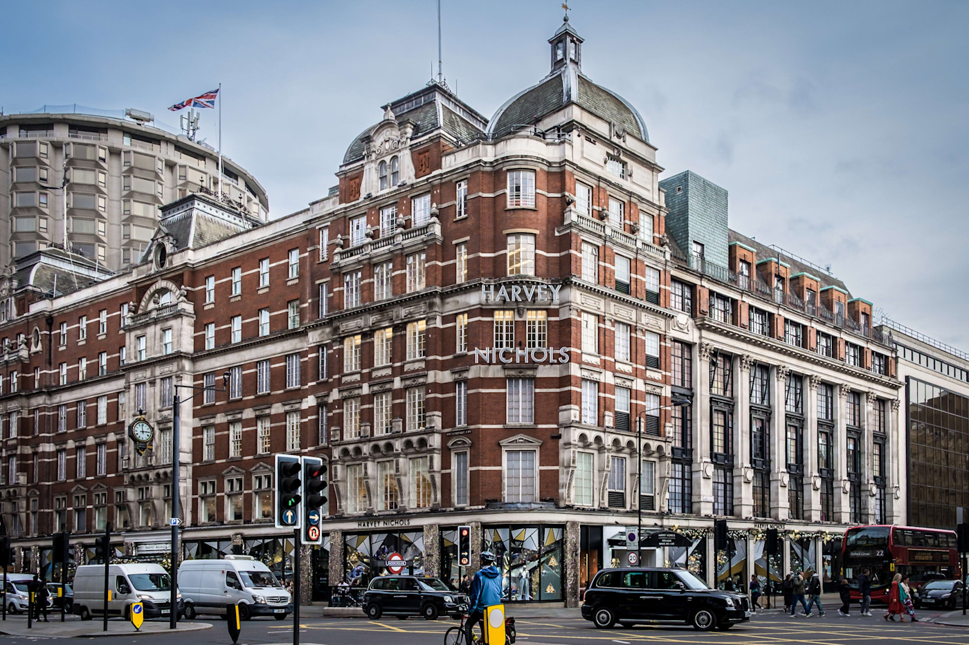 보행자와 차량, 자전거 이용객이 오가는 런던의 혼잡한 교차로에 위치한 Harvey Nichols 플래그십 스토어 전경.