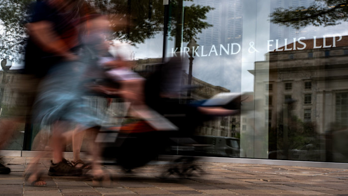 유리 건물에 커클랜드 앤드 엘리스(Kirkland & Ellis)라는 이름이 보이고, 흐릿한 사람들이 지나가며 움직임과 활기를 암시한다.