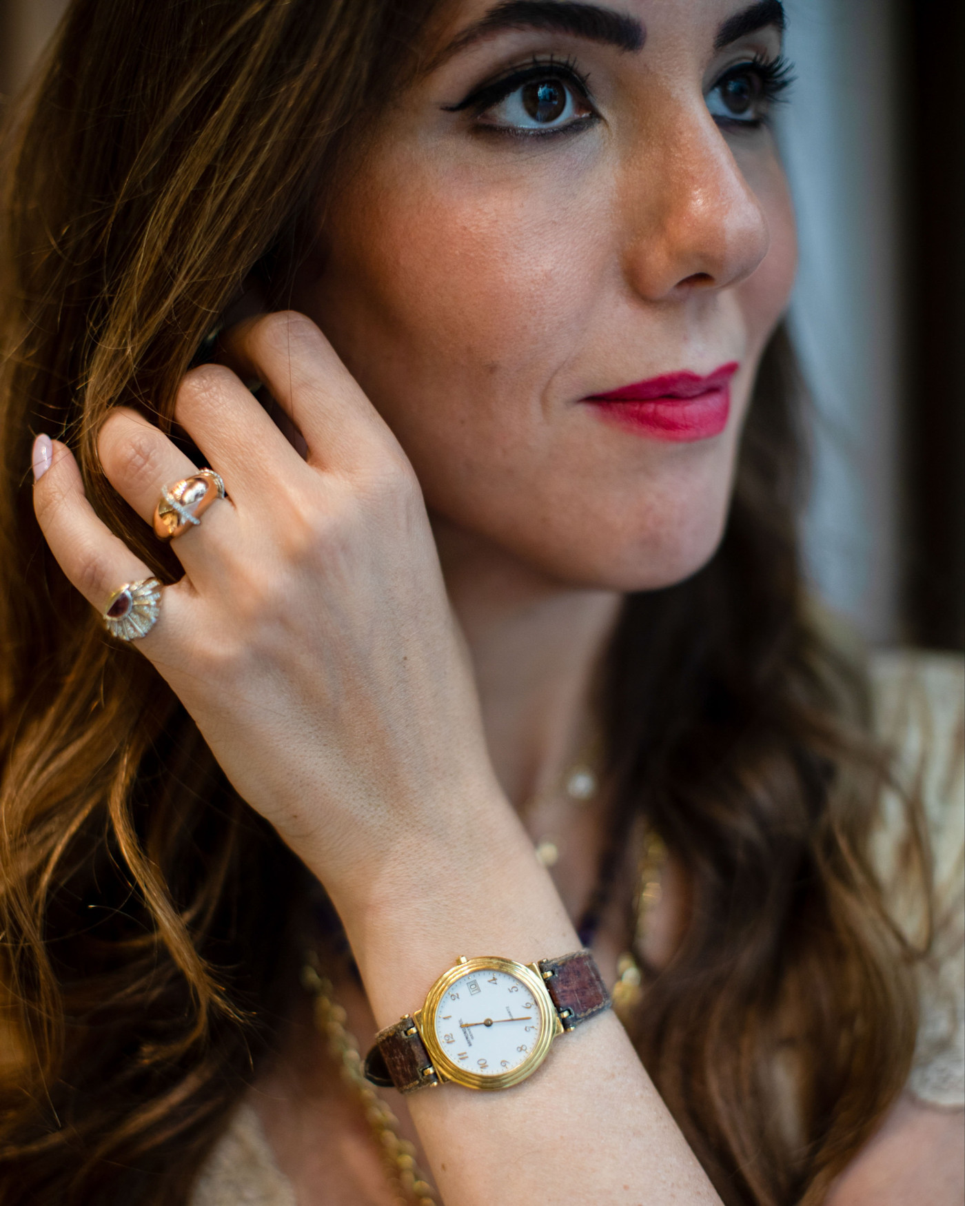 L’Atelier Nawbar 안에서 빈티지 Raymond Weil 시계와 반지 두 개를 착용하고 얼굴 가까이에 손을 댄 Tania Nawbar.