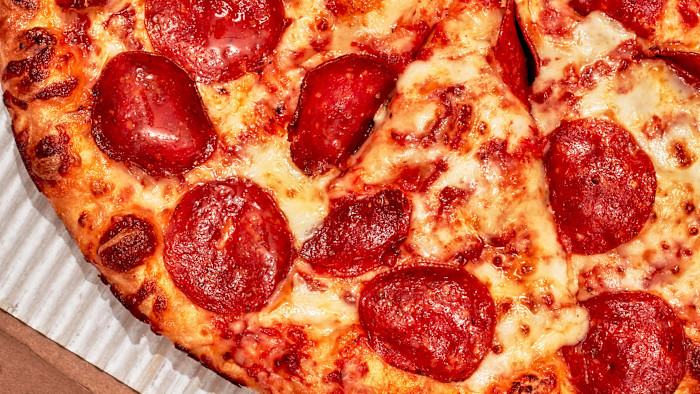 페퍼로니 슬라이스와 녹인 치즈를 올린 Domino’s 팬 피자의 클로즈업.