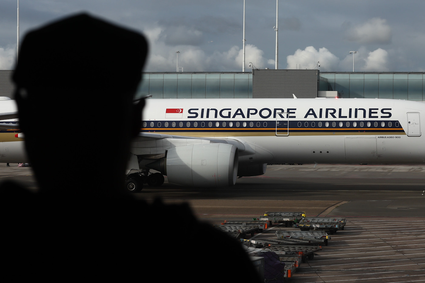 공항 게이트에 주기된 Singapore Airlines Airbus A350-900 여객기와 전경에 보이는 사람의 실루엣.