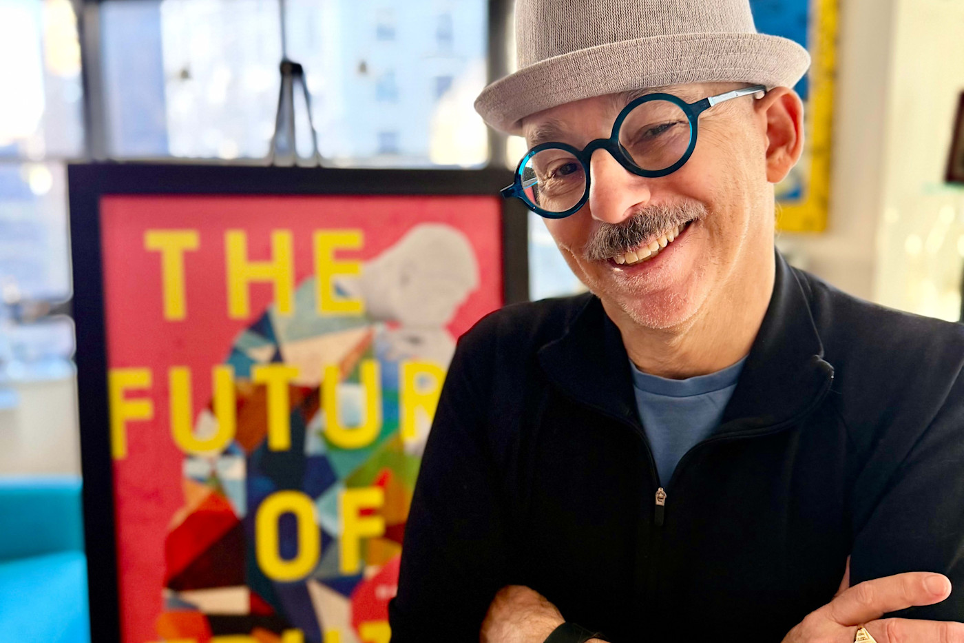 Steven Rosenbaum이 ‘The Future of Truth’라는 문구가 표시된 포스터 앞에서 팔짱을 낀 채 미소 짓고 있다.