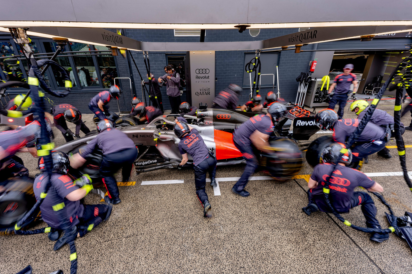 팀원들이 빠르게 타이어를 교체하는 가운데 피트 크루가 Nico Hülkenberg의 Audi Revolut F1 차량으로 피트스톱을 연습하고 있다.