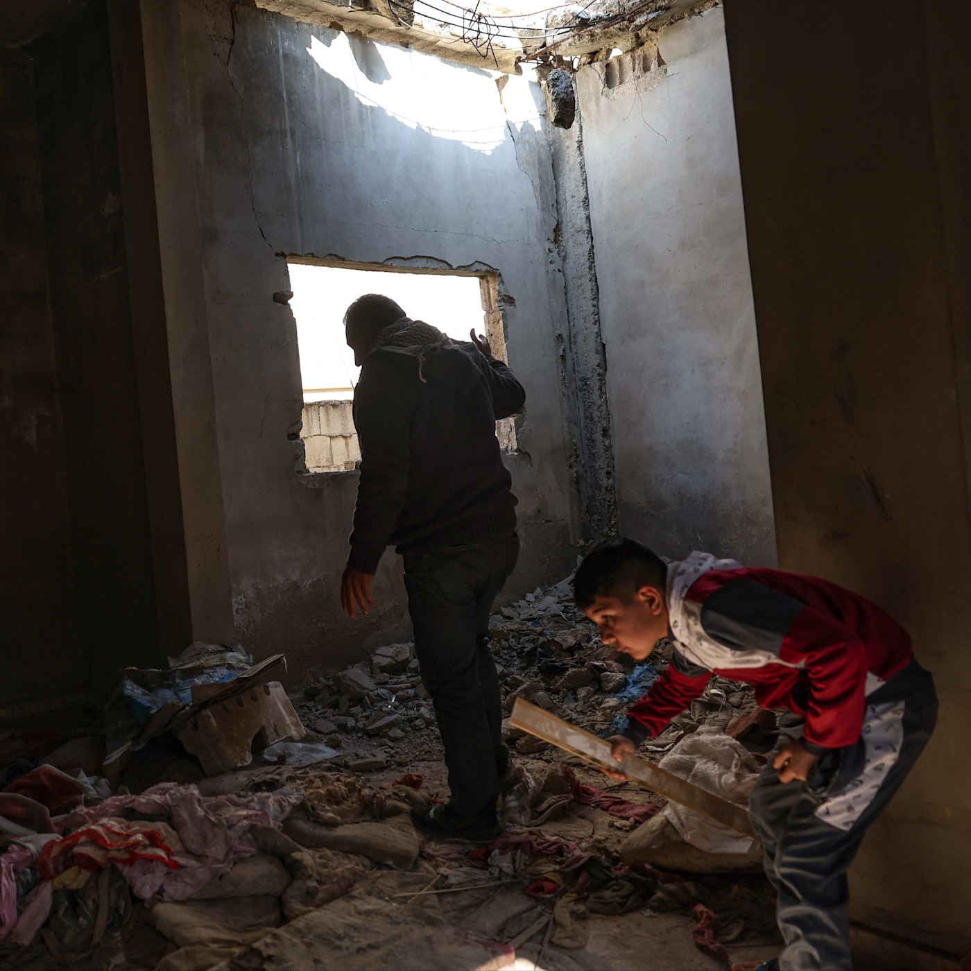 Fayez al-Jammal walks with one of his children amid debris inside his severely damaged home in Homs, Syria.