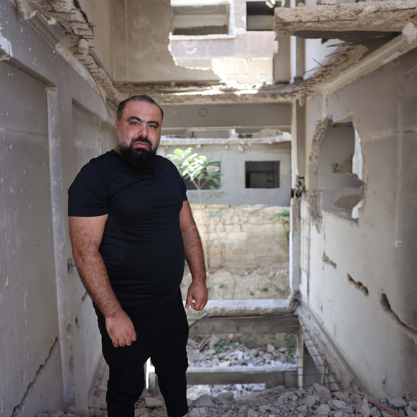 A man stands amid rubble inside a heavily damaged, partially destroyed building in Jobar, Syria.